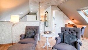 Ein gemütliches Schlafzimmer im Loft-Stil mit zwei Sesseln, einem kleinen Tisch und einer Treppe, die in eine obere Ebene führt.