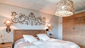Ein Schlafzimmer mit einem großen Bett, zwei Nachttischlampen, einem Wanddekor und einem Holzschrank.