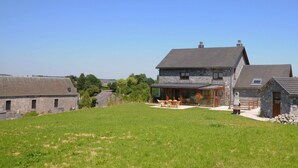 A stone house with a large patio, a dining area, and a small garden. - Stone House in Durbuy With Sauna & Garden Views (Somme-Leuze)