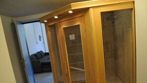 A room with a wooden wardrobe, a door leading to another room, and a small seating area with cushions. - Stone House in Durbuy With Sauna & Garden Views (Somme-Leuze)