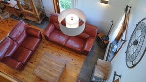 A spacious living area with leather sofas, a wooden coffee table, and a large floor lamp. - Stone House in Durbuy With Sauna & Garden Views (Somme-Leuze)