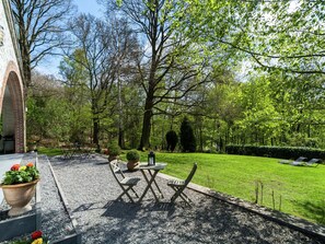 A courtyard with a table and chairs, surrounded by a well-maintained lawn and trees. - Nice House with Sauna, Fireplace, & Large Garden near Aubel (Dalhem)