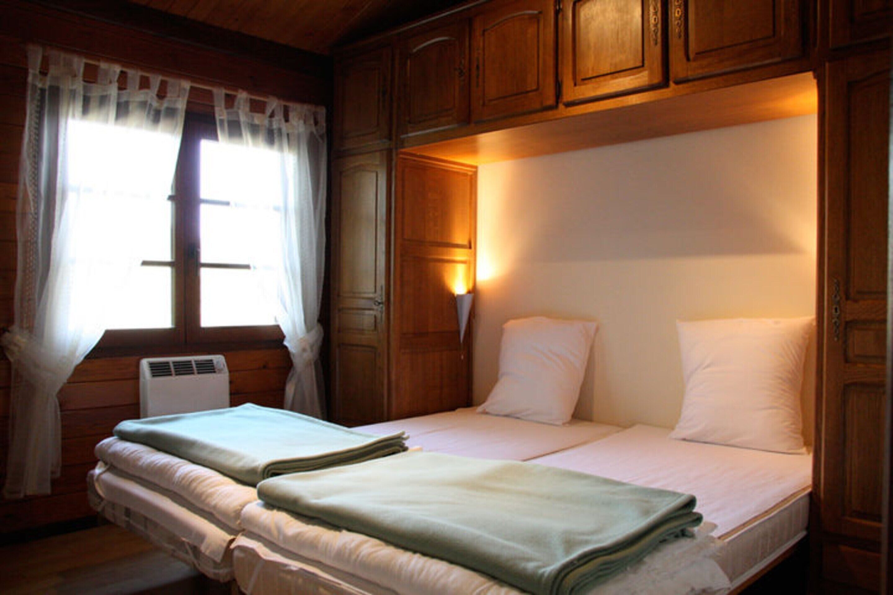 A double bed with white bedding, a bedside table, and a window with curtains.