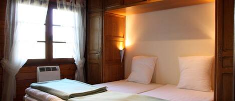 A double bed with white bedding, a bedside table, and a window with curtains.