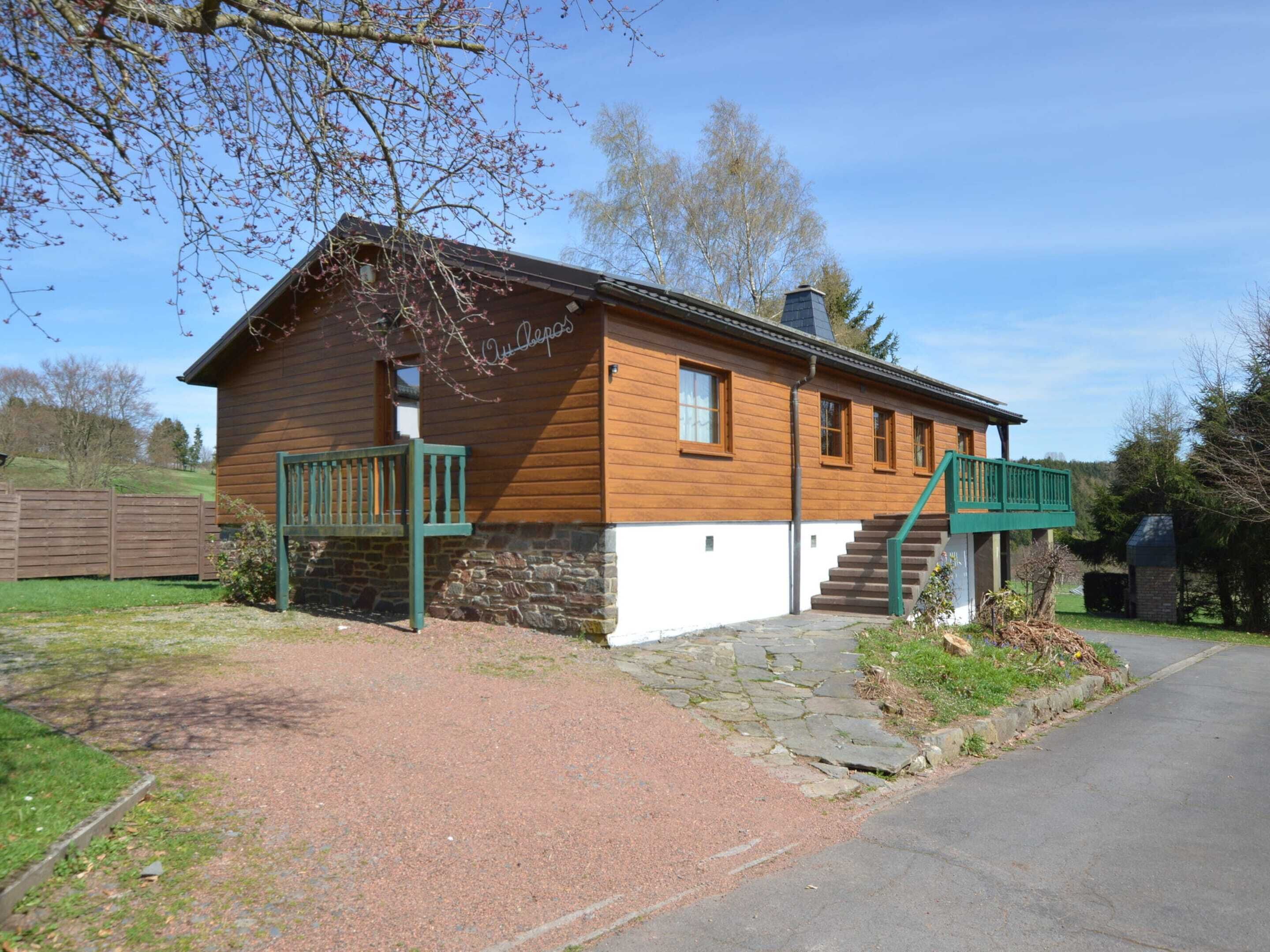 A wooden cabin with a stone foundation, a green porch, and a stone staircase leading to a second level.