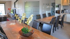 A modern kitchen with a dining area, featuring a central island with a plant, a refrigerator, and a microwave.