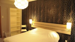 A hotel room with a bed, a white headboard, a wall with circular patterns, and two bedside lamps. - Holiday Home in Marche-en-famenne Near Train (Marche-en-Famenne)