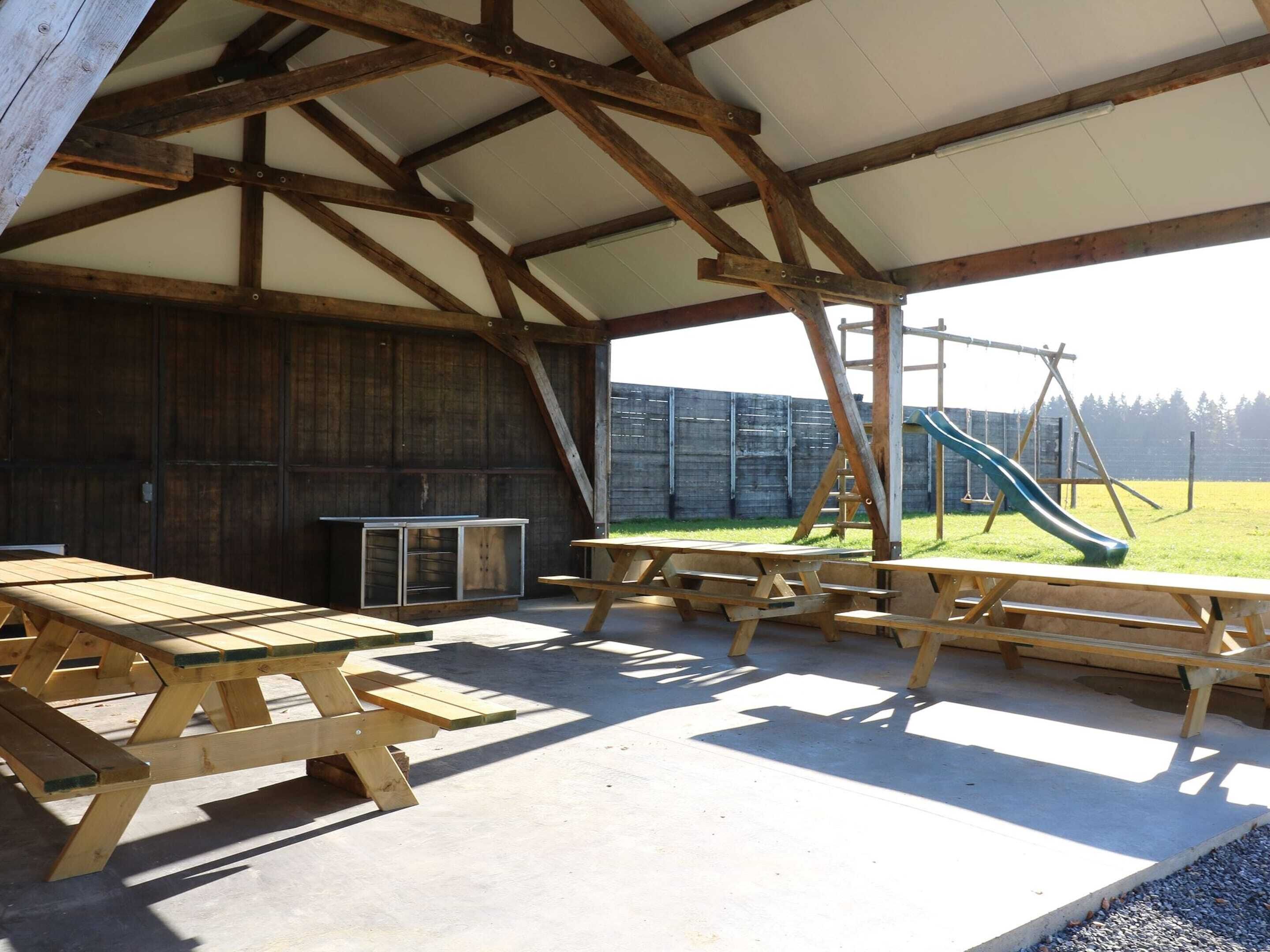An outdoor covered area with picnic tables and a playground.