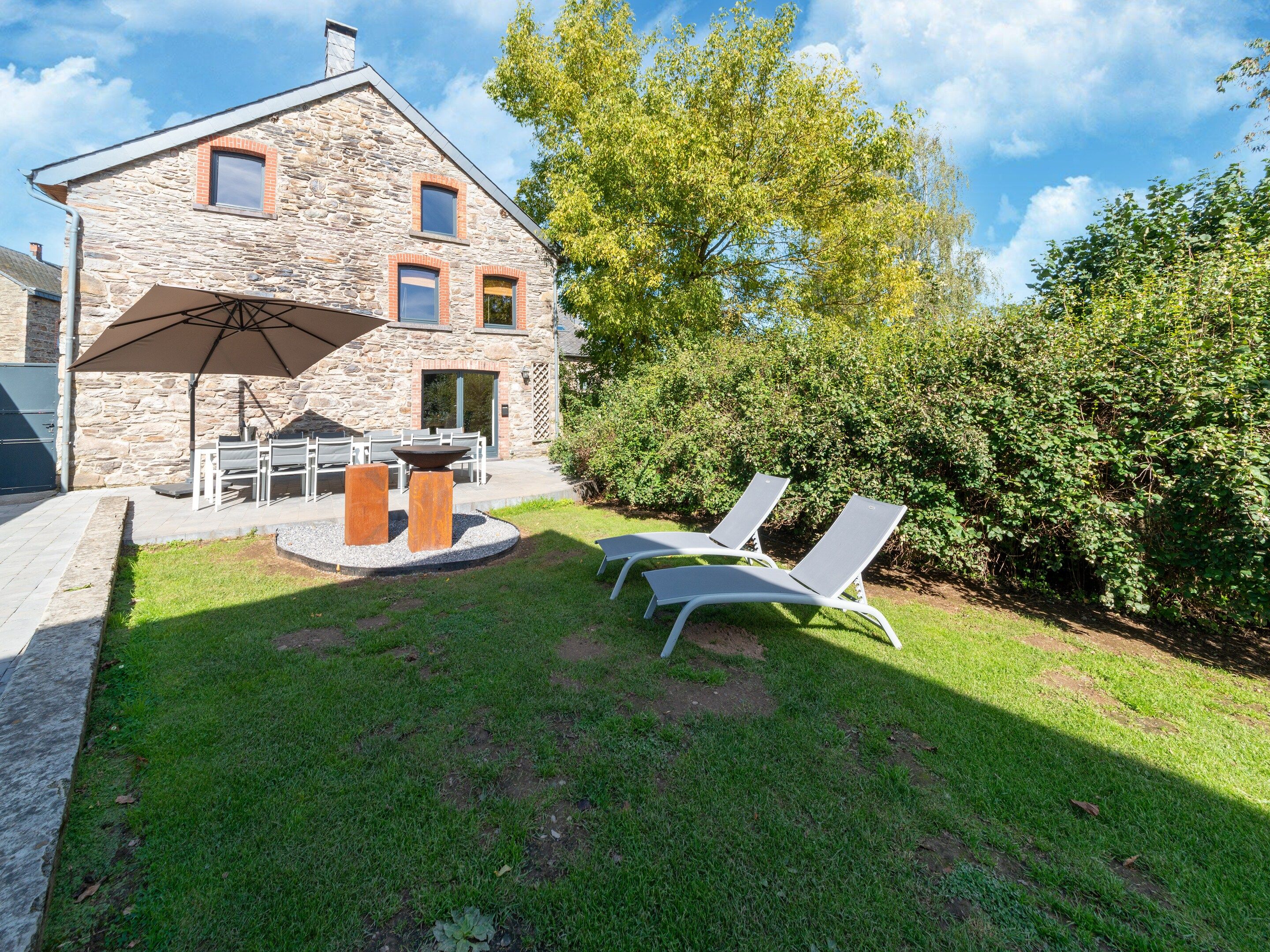 A stone building with a patio area, outdoor seating, and a fire pit.