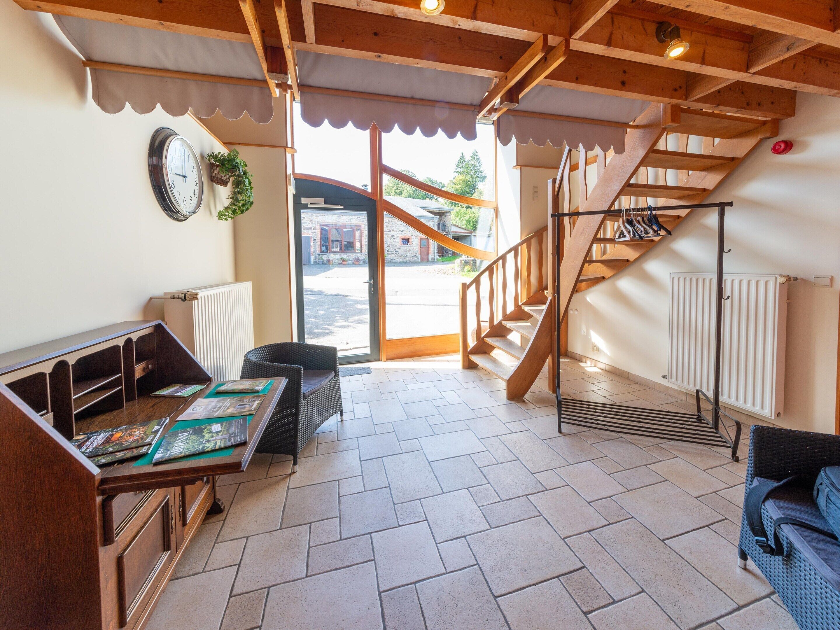 A modern interior with a wooden staircase, a seating area with a table, and a view through a glass door to the outside.