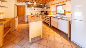 A modern kitchen with wooden beams, white cabinets, and a central island. - Lierneux Family Nature Stay (Lierneux)