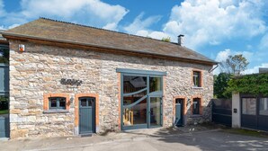 A stone building with a large glass door and a sign reading "Ravabaga." - Lierneux Family Nature Stay (Lierneux)