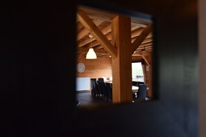 A dining area with wooden beams, a hanging light fixture, and a clock on the wall. - Rendeux Retreat With Sauna (Rendeux)