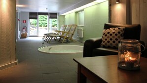 Un cuarto de spa con una camilla de masaje, sillas, una vela y vistas al exterior.