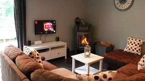 Una sala de estar acogedora con televisión, chimenea y un reloj en la pared.