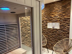 Un interior moderno con un panel de madera, una pared divisoria de vidrio y dos sillas de mimbre.