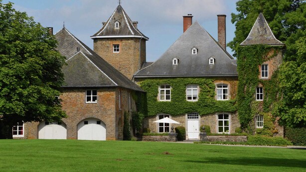 A large, historic stone building with multiple chimneys, a central tower, and ivy-covered walls. - Delightful Castle in Bastogne with Hot Tub (Bastogne)