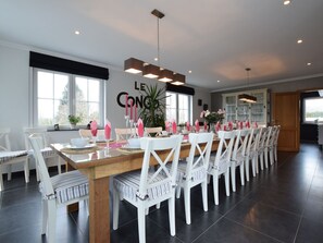 A modern dining area with a long wooden table set for a meal, surrounded by white chairs. - Cottage in Ochamps With Private Pool & Sauna (Libin)