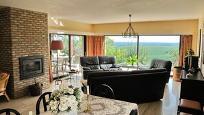 A spacious living room with a fireplace, a sofa, and a dining area with a table set for two. - House in Somme-leuze Near Ardennes Hills (Somme-Leuze)