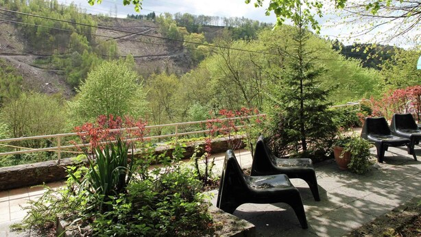 Eine Terrasse mit Sitzgelegenheiten im Freien, umgeben von Grün und mit Blick auf ein Tal.