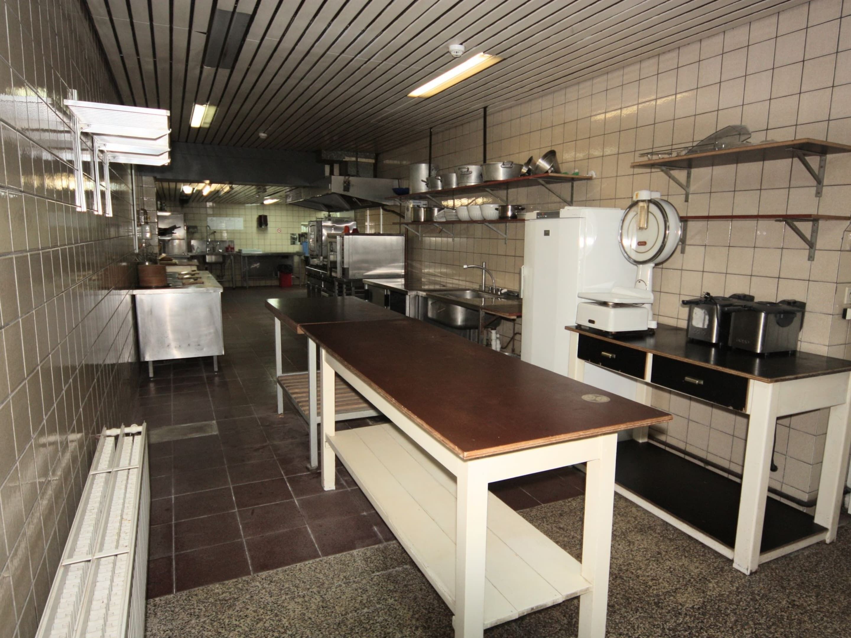 A kitchen with stainless steel appliances, a long counter, and tiled walls.