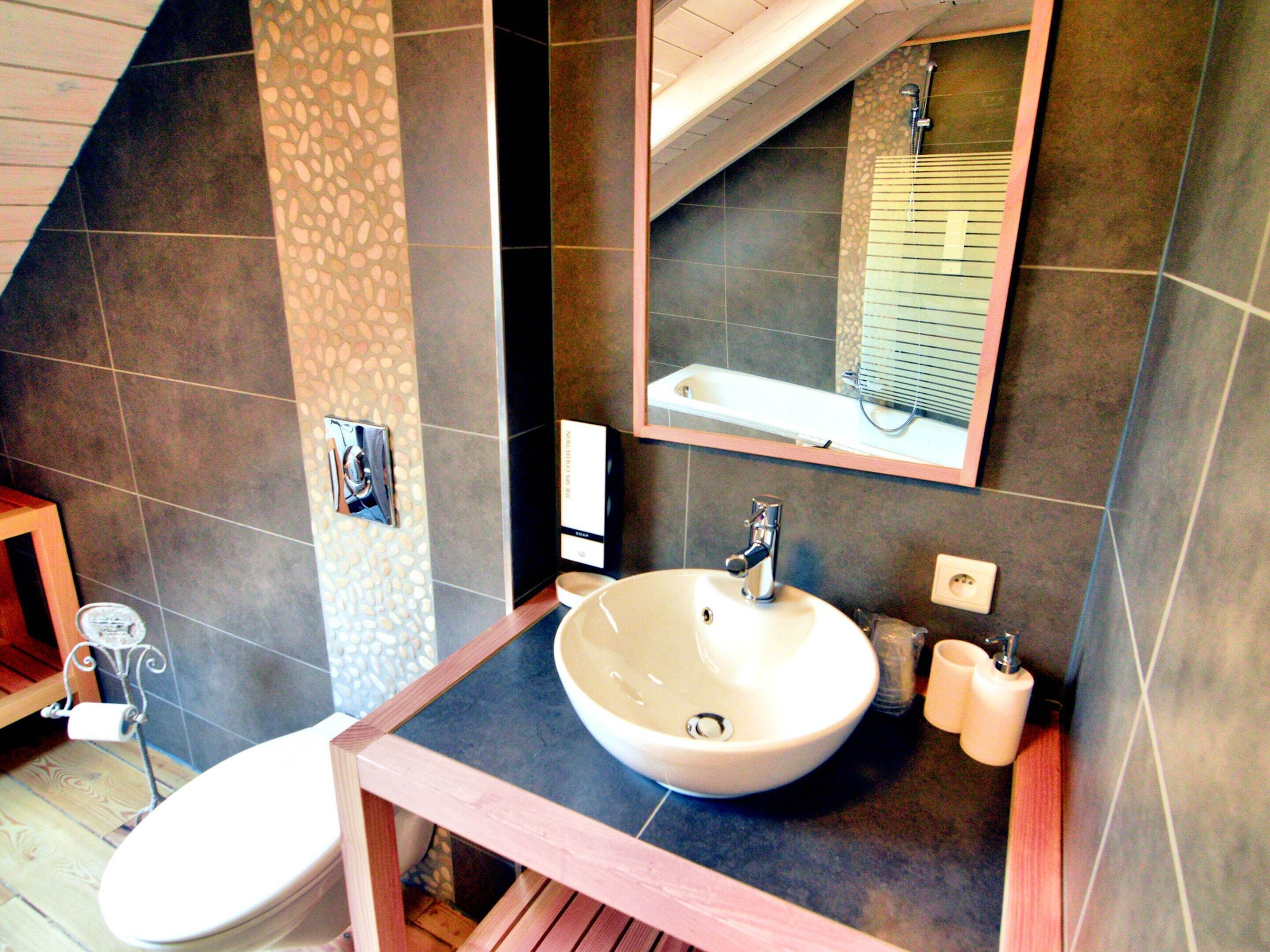 A bathroom with a white sink, a mirror, and a toilet.