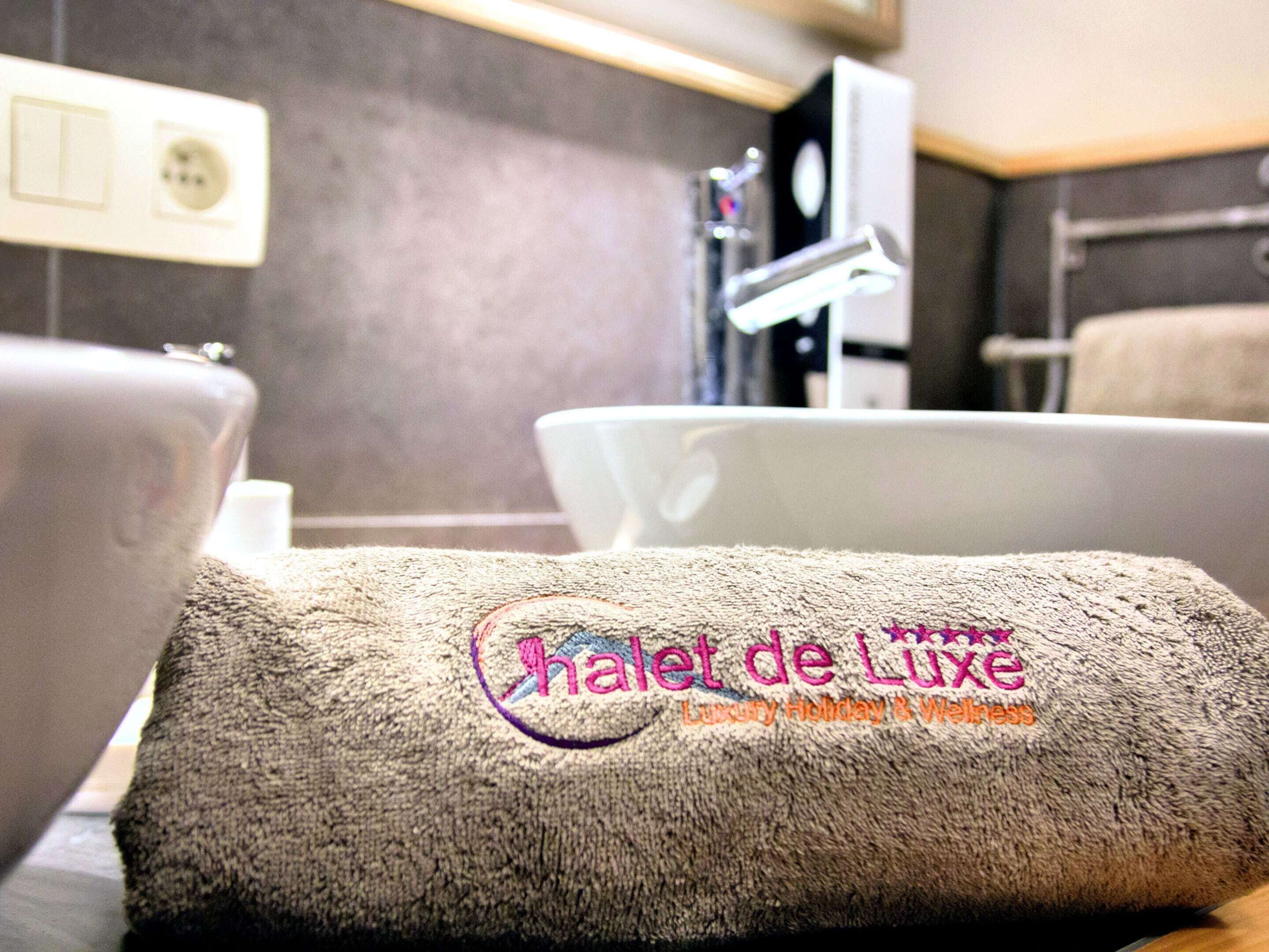 Een handdoek met het logo "Halet de Luxe", wat een luxe hotel aangeeft.