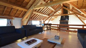 A spacious loft with high ceilings and exposed wooden beams, featuring a modern living area with sofas, a coffee table, and a fireplace. - Holiday Home in Ardennes With Pool & Sauna (Vielsalm)