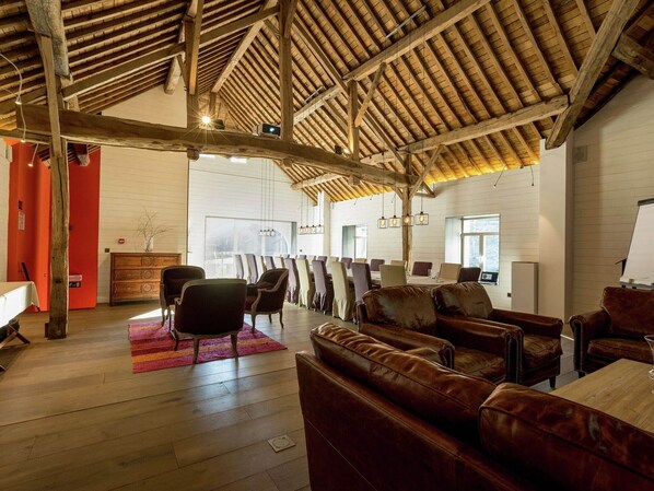 A spacious room with wooden beams, leather sofas, and a large dining table.