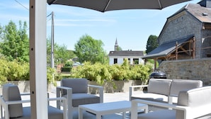 An outdoor patio area with white furniture, including sofas and a table, under a large umbrella. - Cozy Holiday Home in Gedinne near Forest (Gedinne)