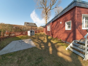 A red wooden house with a chimney, a concrete patio, and a white staircase. - Charming Cottage Near Lake (Waimes)