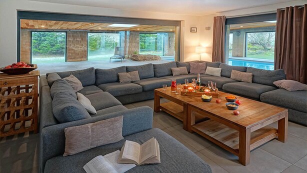 Una sala de estar moderna con un sofá seccional, una mesa de centro de madera y un ventanal con cortinas.