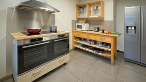 Et kompakt køkken med indbygget ovn, mikroovn og køleskab i rustfrit stål.