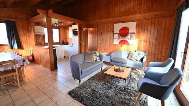 Ambiente in legno con zona pranzo, divano e cucina sullo sfondo.