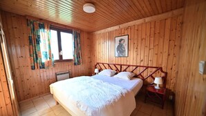 Una camera da letto con pannelli in legno, un letto grande, due comodini con lampade e una finestra con tende.