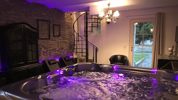 A hot tub with water jets, a stone wall, a staircase, and a chandelier. - Peaceful Holiday Home With Garden in Fauvillers Belgium (Fauvillers)
