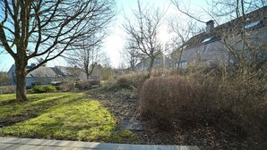 Et boligområde med græsplæne, sti og en bygning med saddeltag.