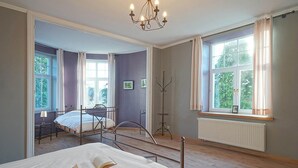 A bedroom with a large bed, a smaller bed, a standing lamp, and a window with curtains. - Chateau in Stavelot With Private Pool & Sauna (Stavelot)