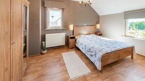Un dormitorio con cama de madera, un radiador, una ventana con vistas y una araña.