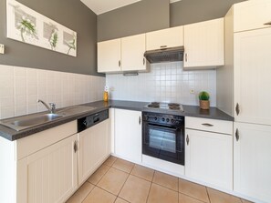 Une cuisine moderne avec des meubles blancs, une cuisinière noire et un évier.