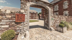 A stone archway leading to a building with a sign that reads "Donnagora Sars." - Castle Farmhouse in Condroz With Heated Pool (Ohey)