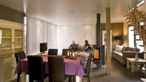 Un interior moderno con comedor, chimenea y zona de estar con una escalera.