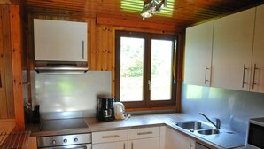 Eine kompakte Küche mit weißen Schränken, einem Edelstahlbackofen, einer Kaffeemaschine und einem Fenster für natürliches Licht.