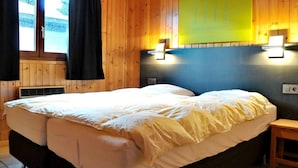 Ein Zimmer mit Holzwänden, einem Bett, einem kleinen Nachttisch und einer Wandleuchte.