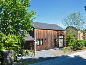 A modern wooden building with a sloped roof, a gated entrance, and a small parking area. - Holiday Home in Houffalize Near Nisramont (Houffalize)