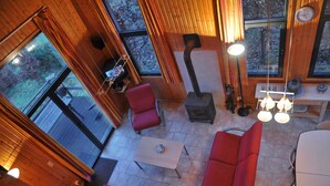 A wooden interior with a fireplace, red seating, and a table with a clock. - Holiday Home in Houffalize Near Nisramont (Houffalize)