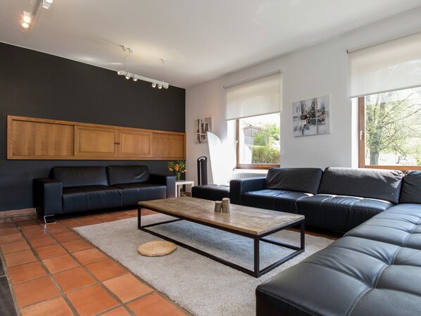 A modern living room with two black leather sofas, a wooden coffee table, and a grey rug.