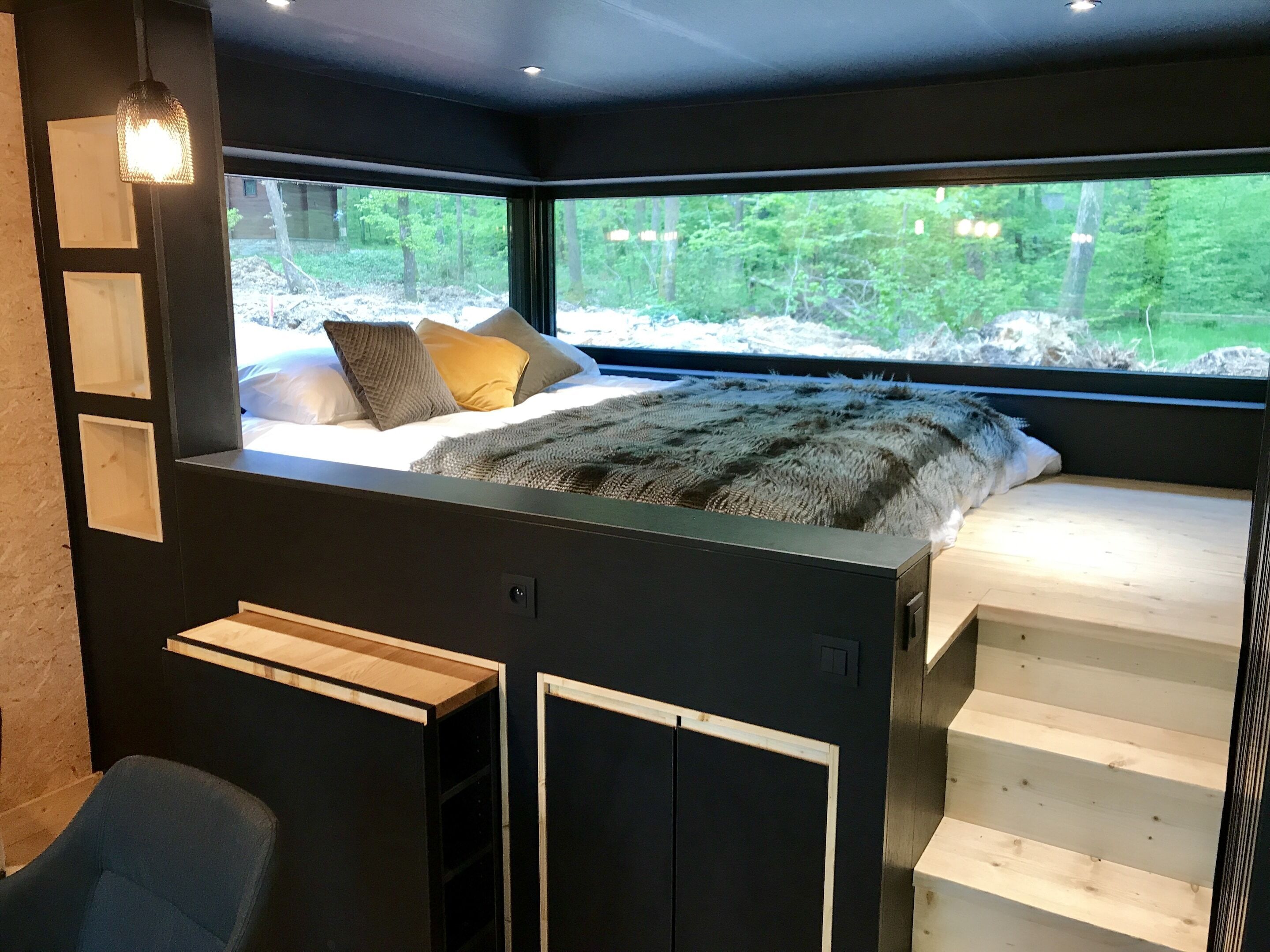 A bedroom with a bed, a window, and a staircase.