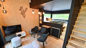 A modern interior with a bed, seating area, and a staircase. - Lodge in Oignies Forest With Eco Design (Viroinval)