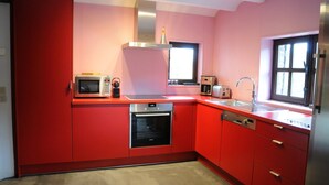Eine moderne Küche mit roten Schränken, Edelstahlgeräten und einem Fenster, das für natürliches Licht sorgt.